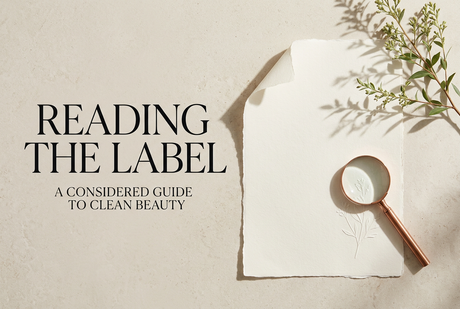 Reading the Label: A Considered Guide to Clean Beauty, with ivory paper, a copper magnifying glass, and a botanical branch.